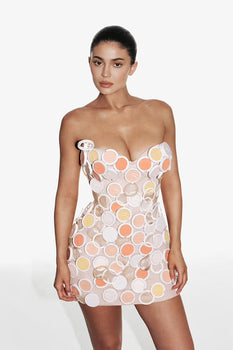 Kylie Jenner in a strapless minidress made from Kylie Cosmetics powder compacts against a white background