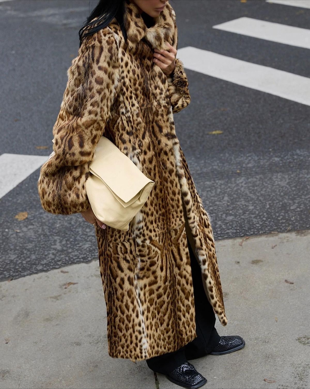 Street-style reference: full-length leopard coat styled with black trousers and a cream bag