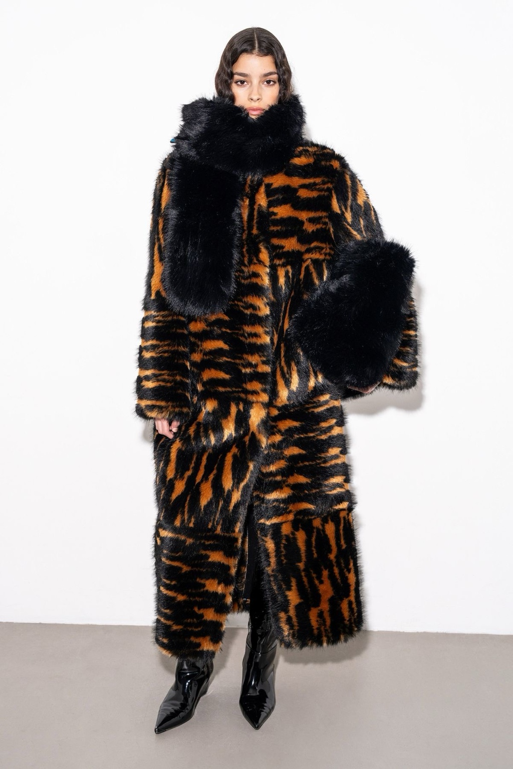 Model wearing a dramatic tiger-print faux-fur coat with oversized black cuffs and collar