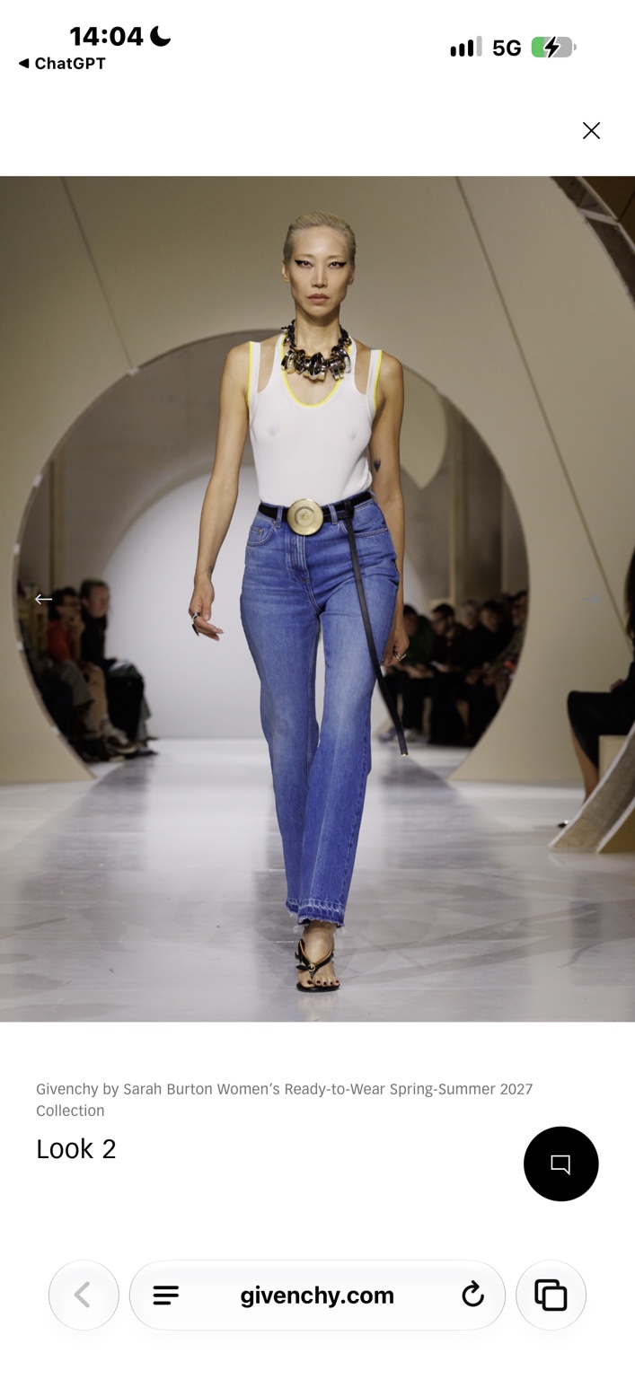 White vest and blue jeans with a sculptural disc belt and wiry heels