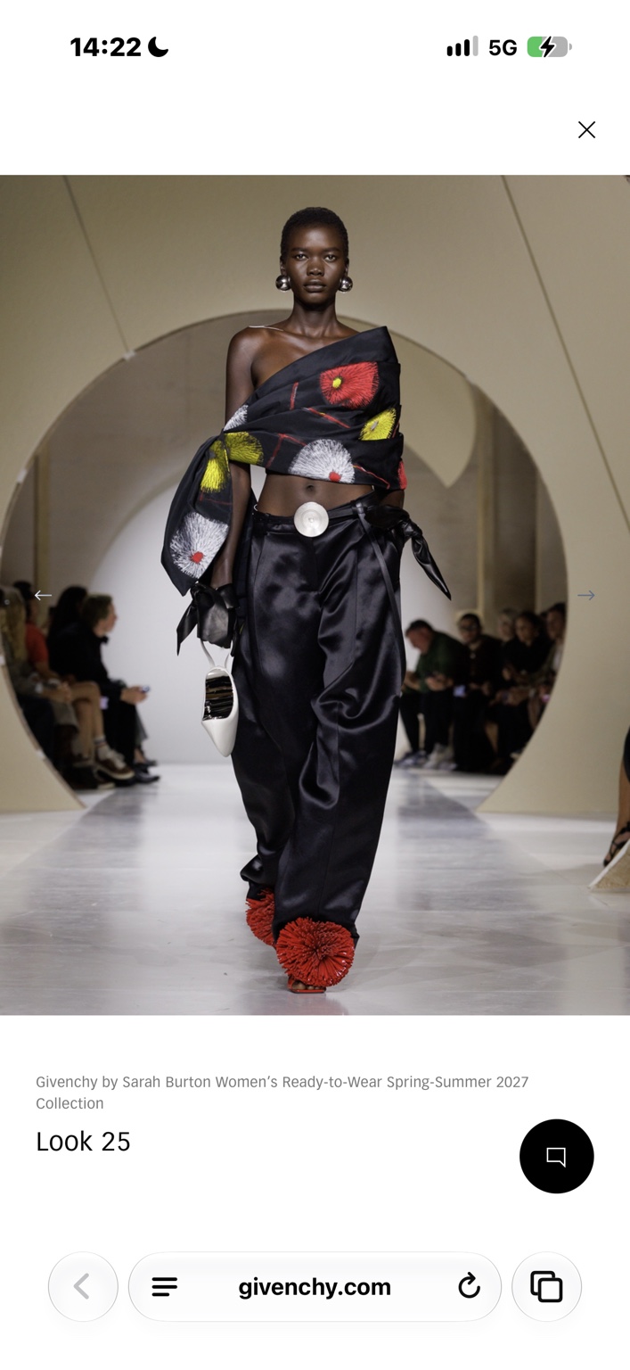 Black satin trousers and wrapped floral top with red pom-pom shoes