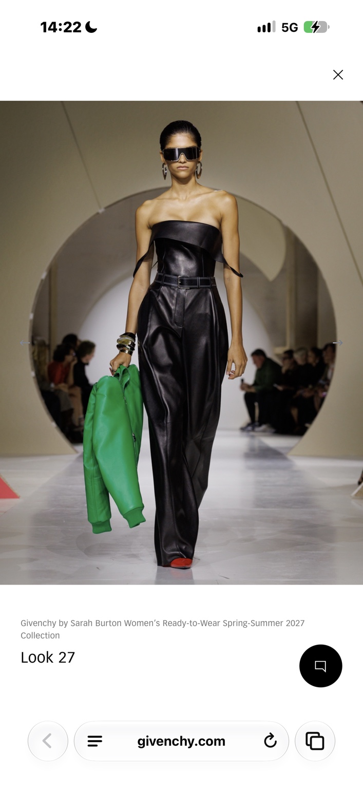 Strapless black leather jumpsuit carrying a bright green jacket