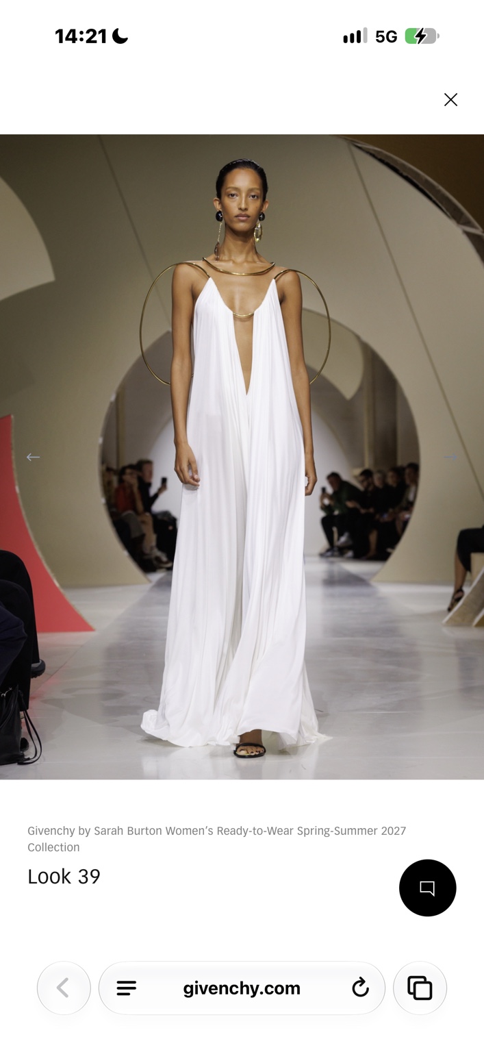 Fluid white gown suspended from a sculptural gold structure