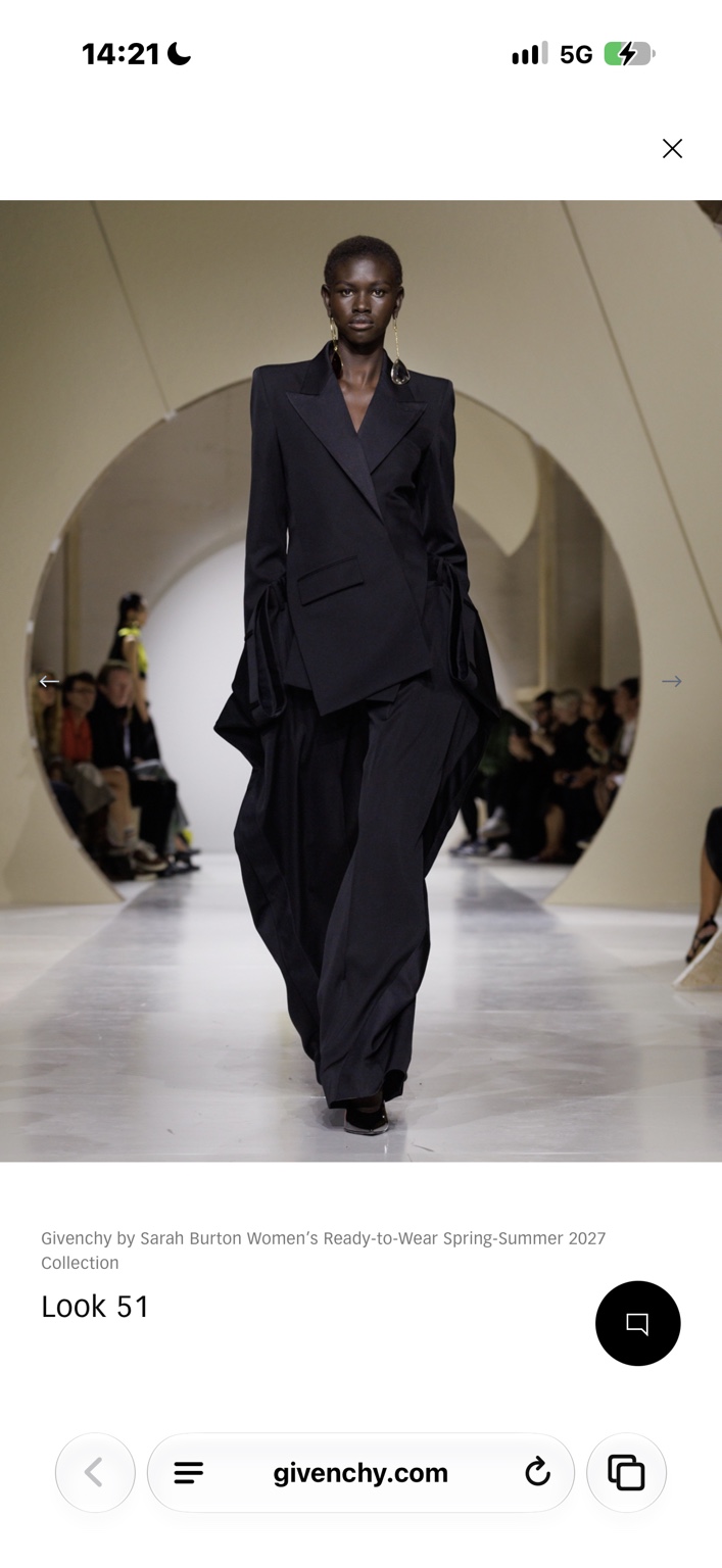 Black jacket with vast folded trousers and long sculptural earrings