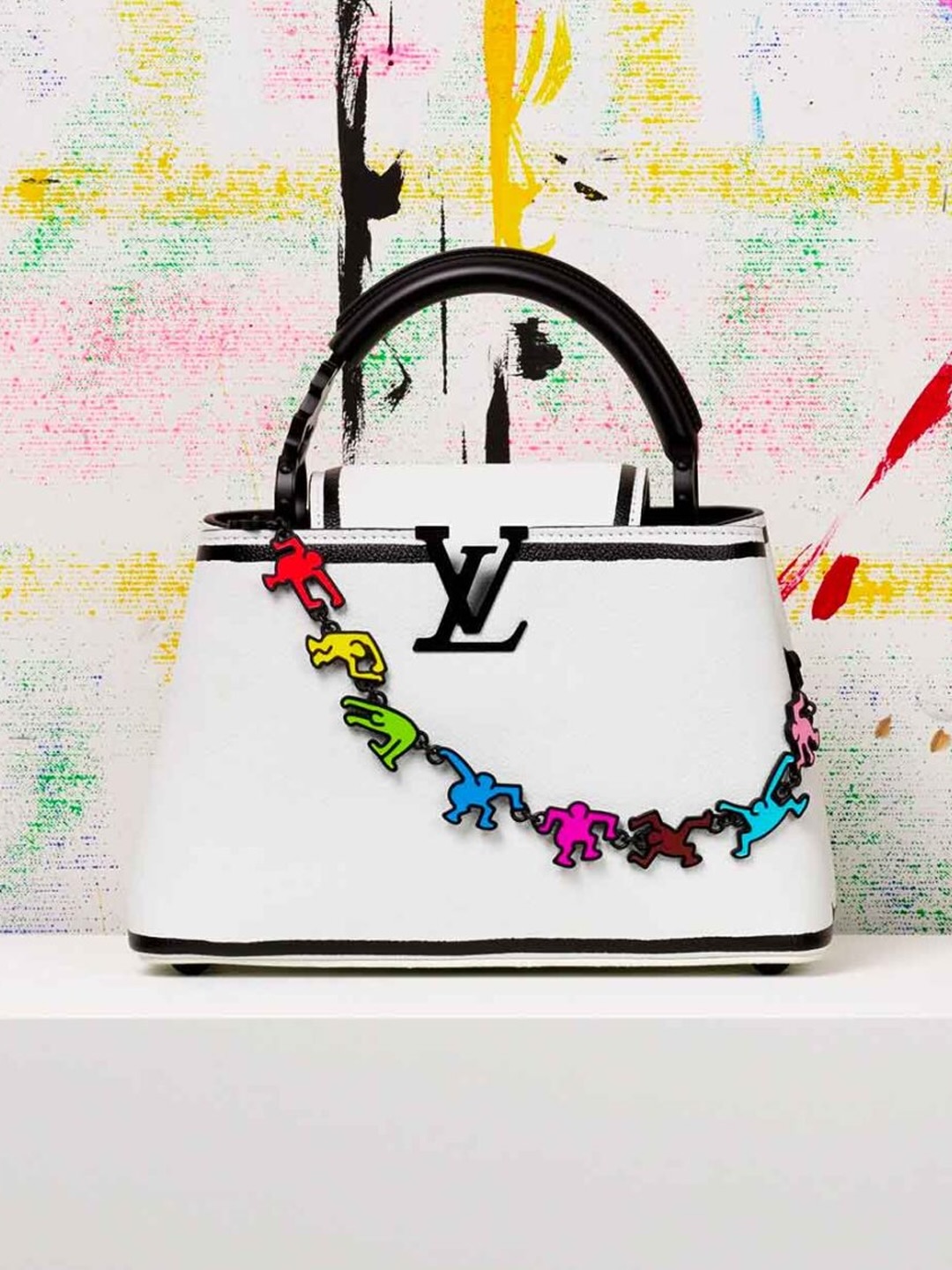 White Louis Vuitton Capucines bag with a chain of colourful Keith Haring figure charms