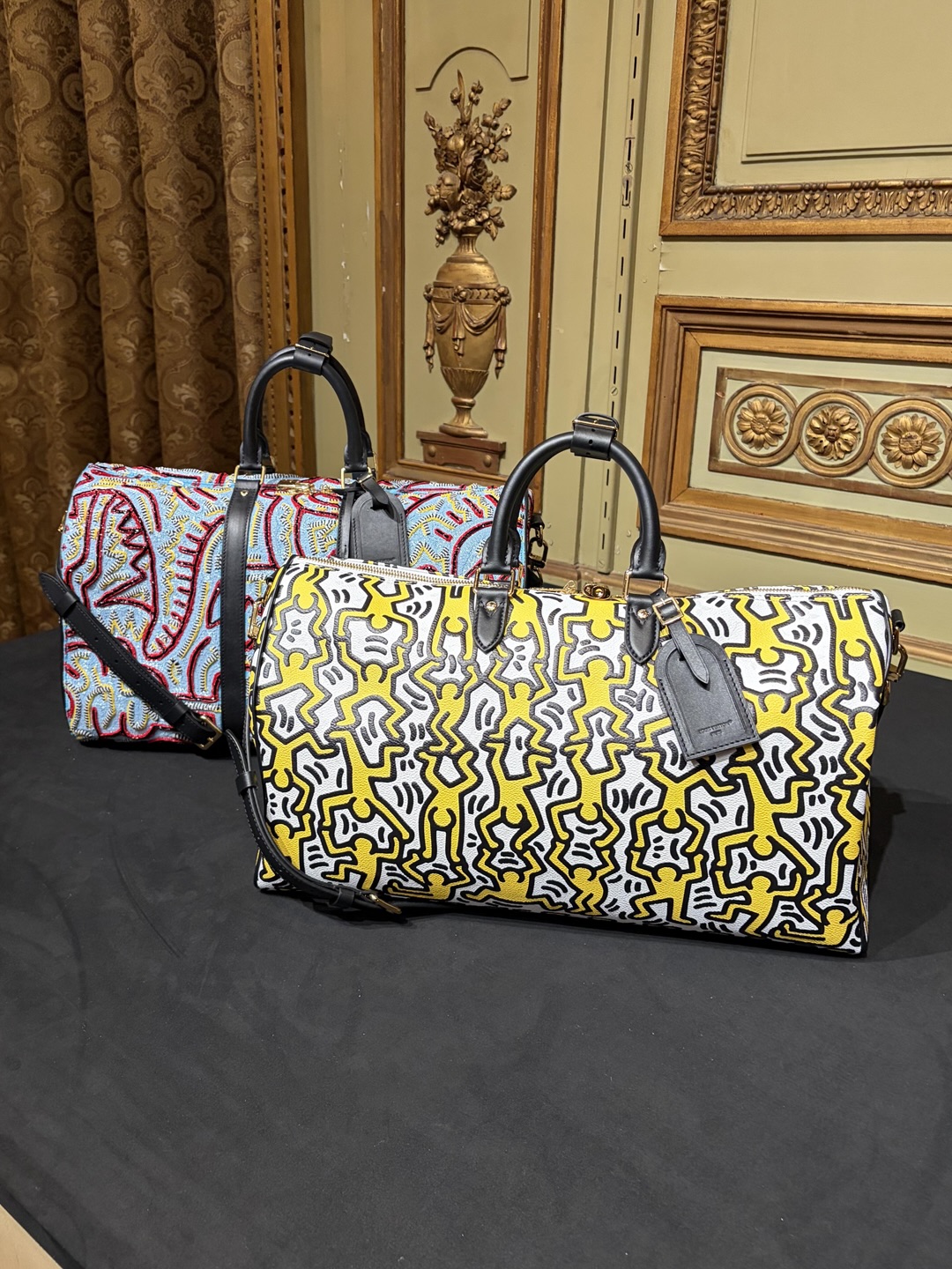 Two Louis Vuitton Keepall bags covered in colourful Keith Haring figures