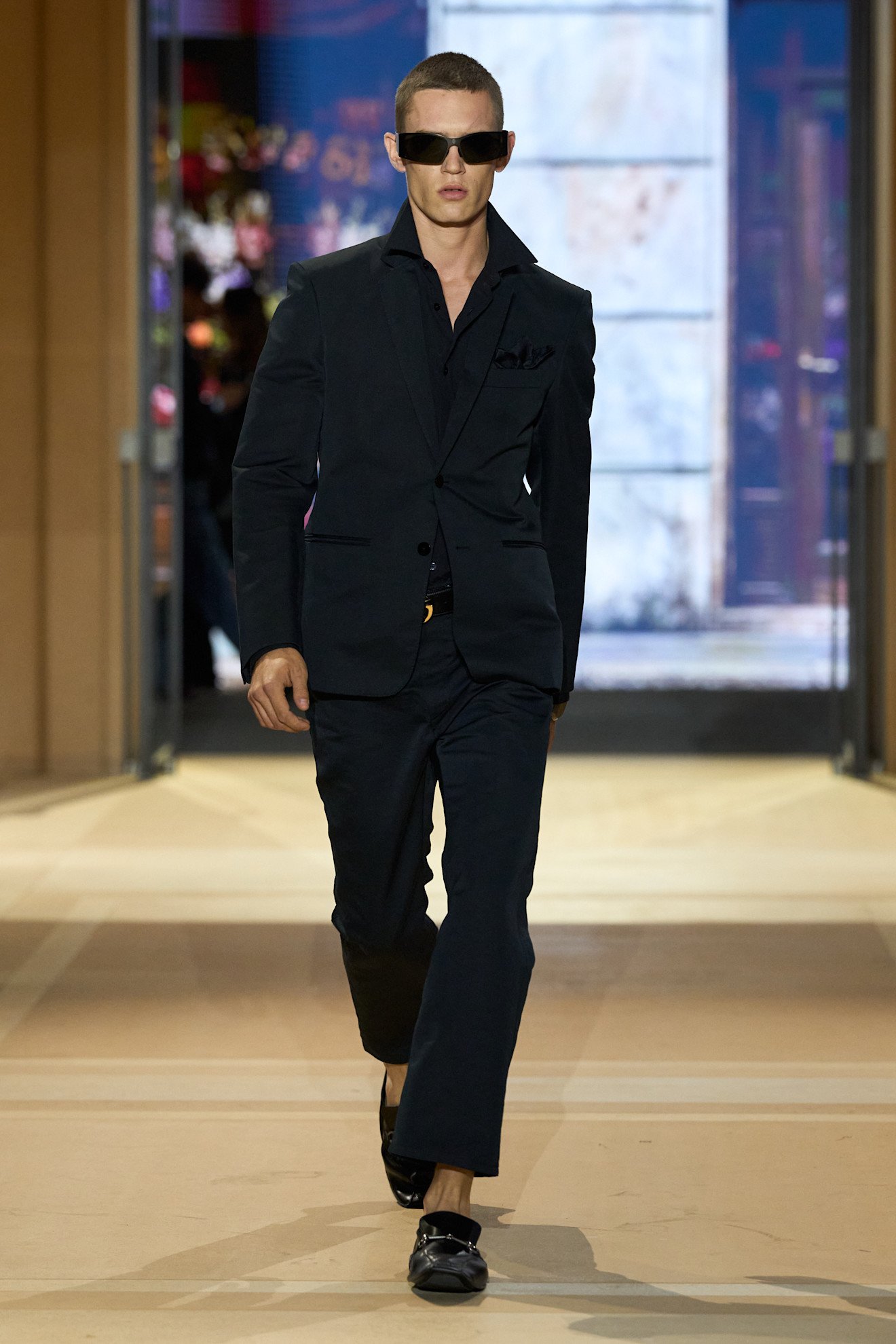 Model in a black Gucci suit walking through the house’s shop-inspired Spring 2027 show