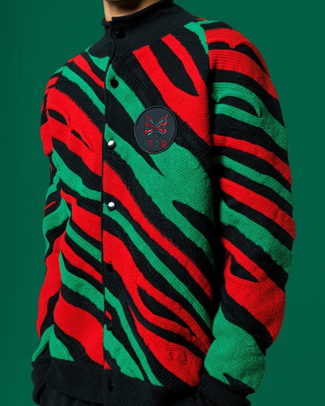 Close view of the red, green and black Needles x A Tribe Called Quest roll-neck cardigan