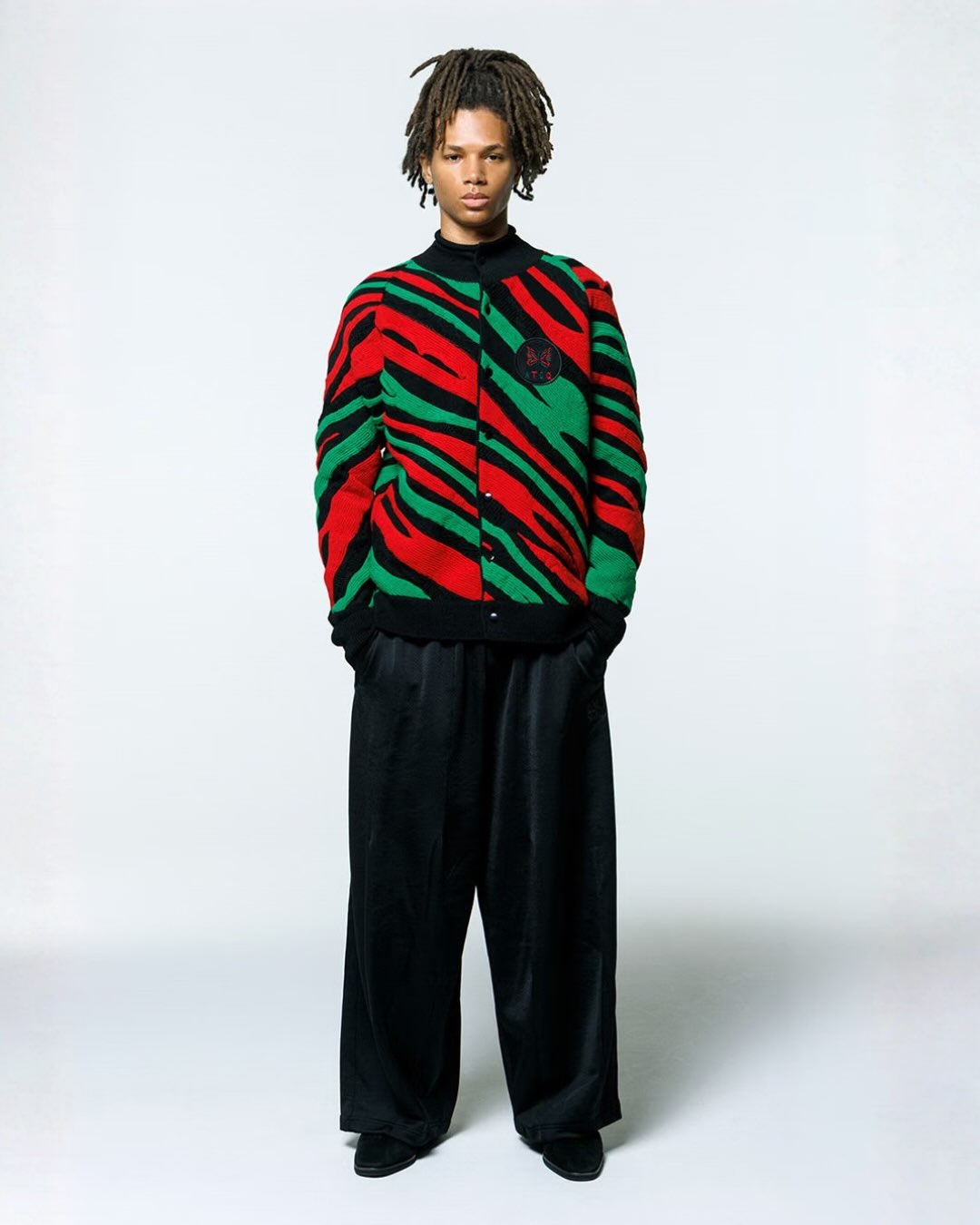 Model wearing the Needles x A Tribe Called Quest red, green and black roll-neck cardigan