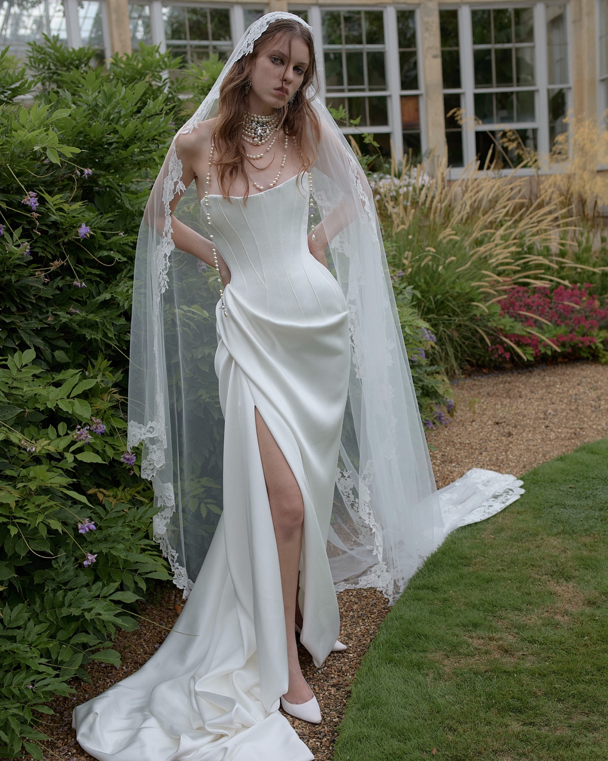 Vivienne Westwood ivory satin corset gown with a thigh-high split and pearl jewellery